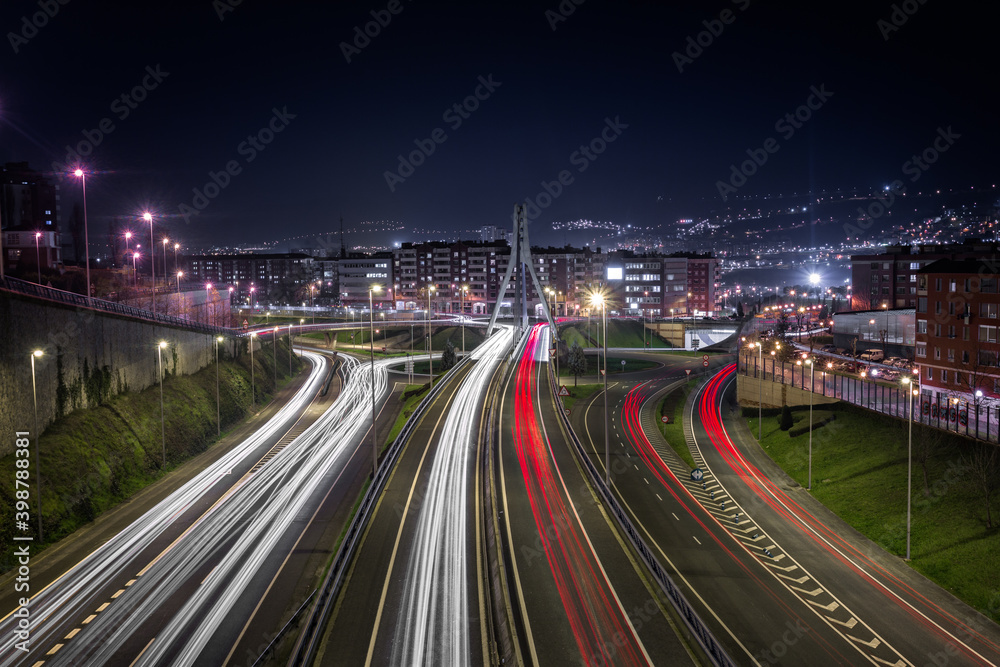 Bilbao, Pais Vasco, Vizcaya, entrada a la ciudad. Alto tráfico nocturno, puente y gran complejo de carreteras, gran ciudad iluminada estelas de coches y autobuses.
