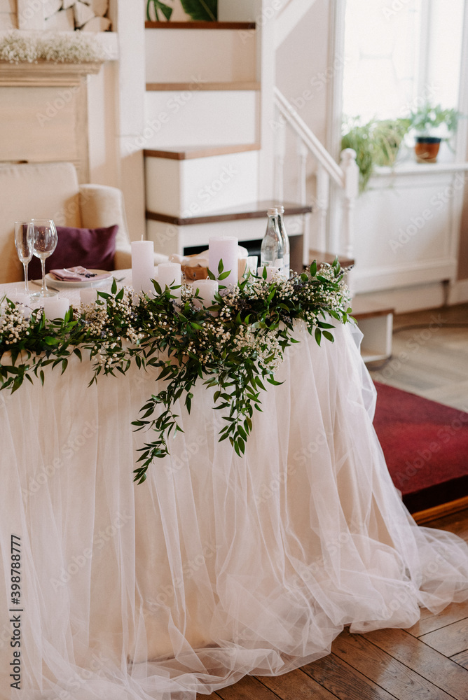 the presidium of the newlyweds in the banquet hall of the restaurant is decorated with candles and green plants