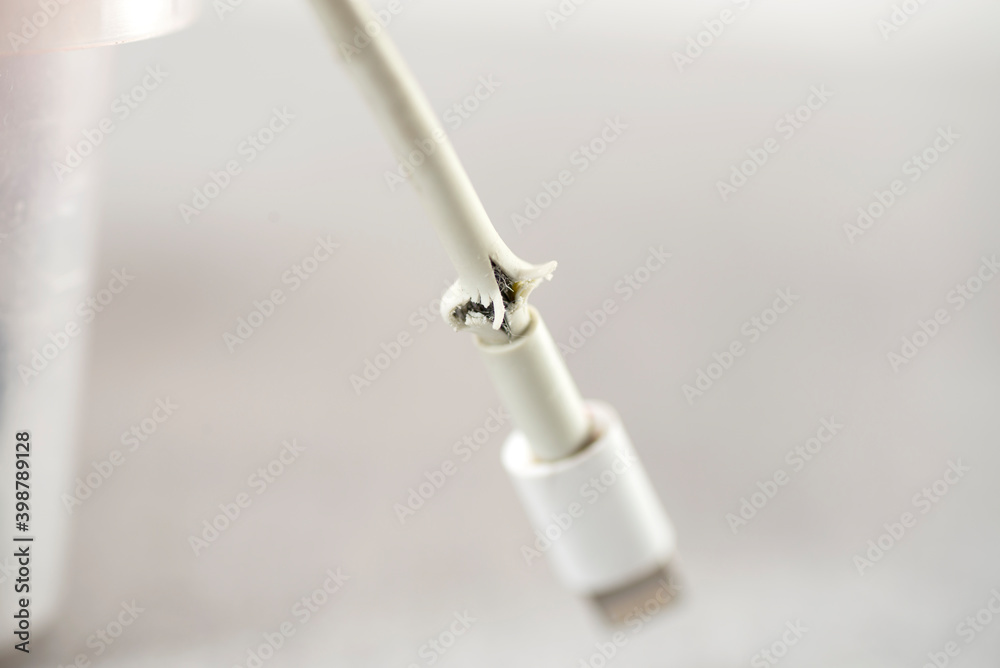 Close up of broken smart phone charger cable on light background Close up of broken smart phone charger cable on light background