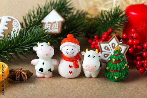 Year of the Bull. Christmas decorations on a beige cardboard background. Figures of bulls  snowman  ginger cookies  anise seeds  spruce branches  red berries and other New year decorations.
