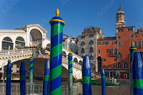 Ponte di Rialto and the Grand Canal, Venice, Italy: brightly painted mooring posts (palina) in the foreground photo