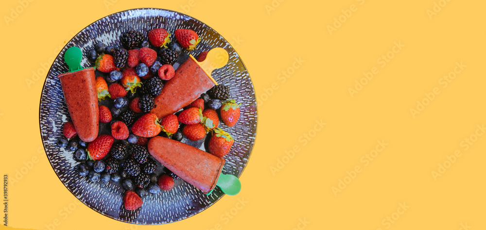Top view of beautiful plate with raspberries, blueberries, strawberries and and homemade berry ice cream (sorbet). Concept of food for children and homemade desserts. Yellow background. Banner.