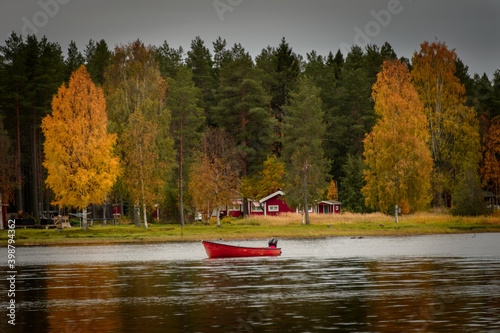 little red boat on the lake in autumn near the red houses