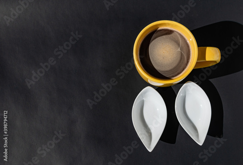 Taza de café y contenedores vacíos en fondo oscuro