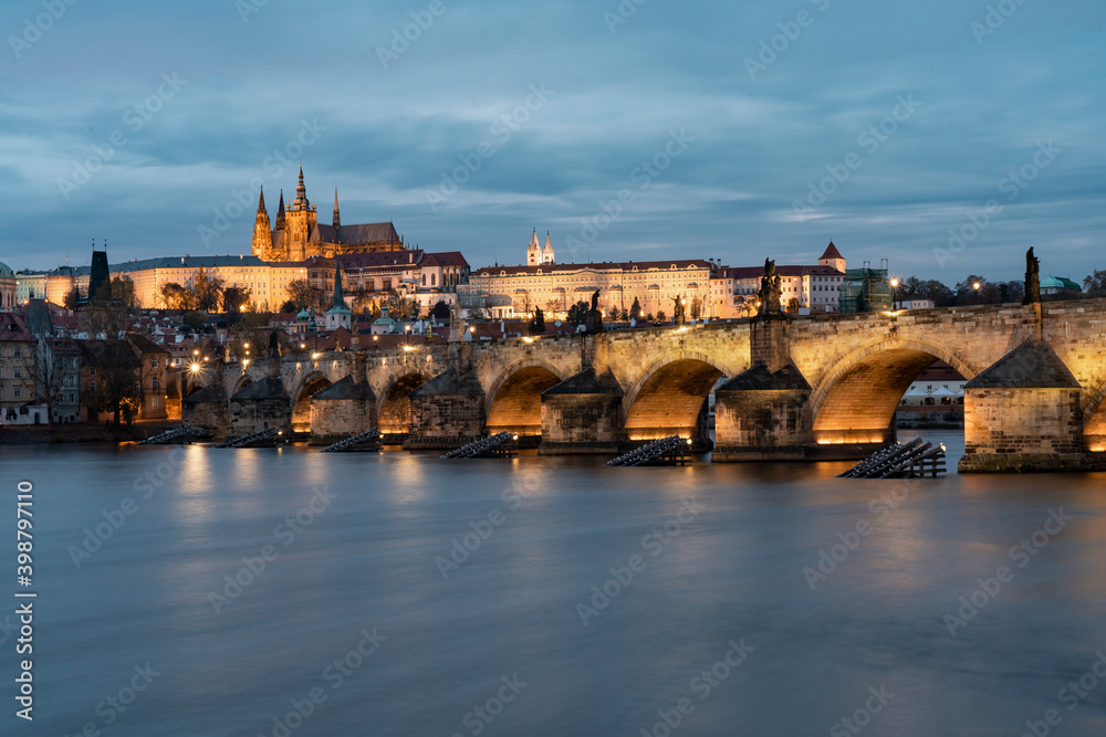 illuminated prague castle and charles bridge and st. vita church lights from street lights are reflected on the surface of the vltava river in the center of prague at night in the czech republic