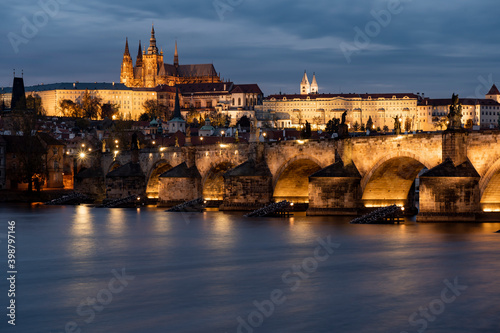 illuminated prague castle and charles bridge and st. vita church lights from street lights are reflected on the surface of the vltava river in the center of prague at night in the czech republic