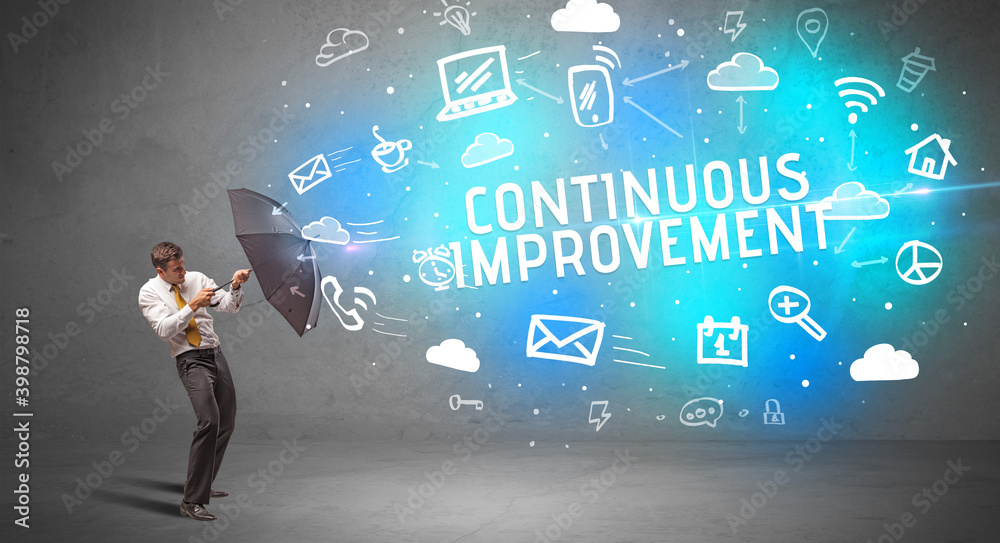 Businessman defending with umbrella from CONTINUOUS IMPROVEMENT inscription, modern technology concept Businessman defending with umbrella from CONTINUOUS IMPROVEMENT inscription, modern technology concept