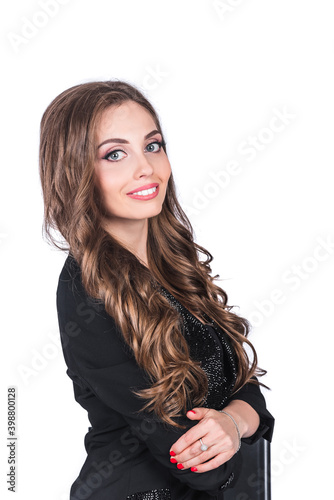 A beautiful woman in a black business suit with a make-up and long hair stands on a white isolated background in the studio. Working and business woman concept