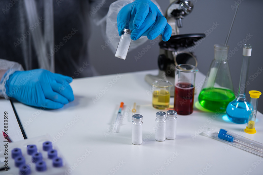 Development and search for drug for coronavirus. Chemist examining ampoule of powdered antibiotic for injection. Treating bacterial infection with medications. Covid 19 health and treatment concept Development and search for drug for coronavirus. Chemist examining ampoule of powdered antibiotic for injection. Treating bacterial infection with medications. Covid 19 health and treatment concept