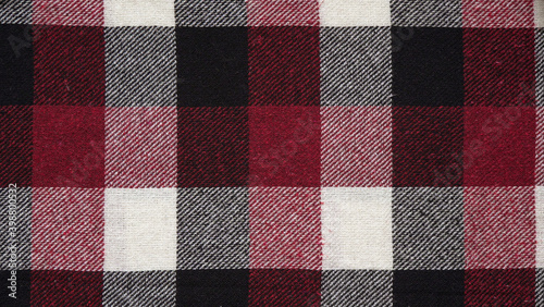 Texture of a woolen red-black-white plaid in a cage, close-up of fabric, textile winter background.Tartan fabric.Checkered pattern