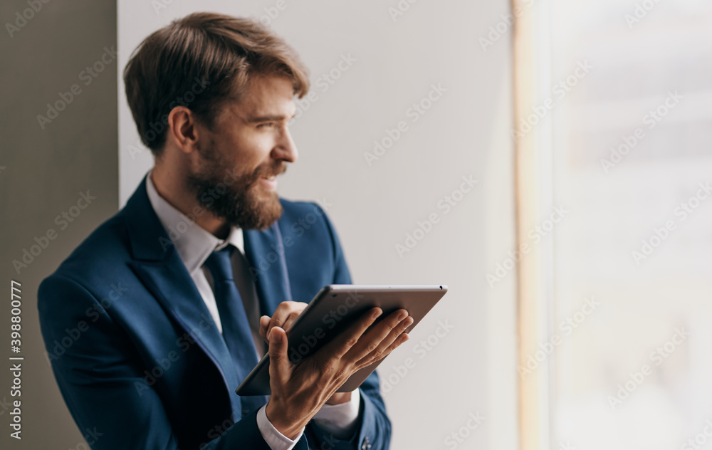 man in suit near the window tablet in the hands of technology Professional businessman