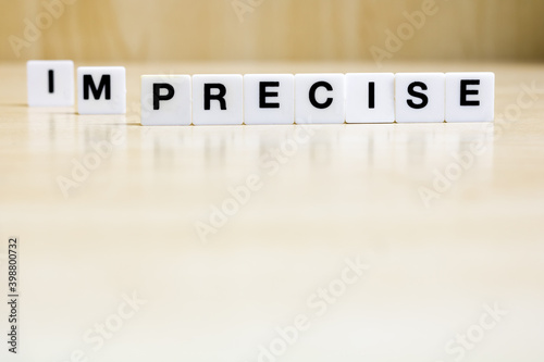 A row of small white plastic tiles, containing the letters forming the word precise, to represents the concept of the transformation of the transition from imprecise to precise.
