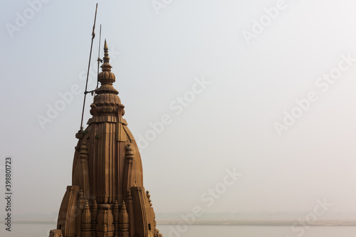 Tower of a temple with the Ganges river in the background in Varanasi, India photo