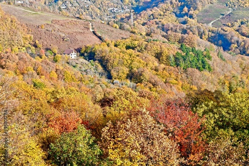 Panorama of mountain peaks to the horizon, covered with mixed forest, with a village on the slopes