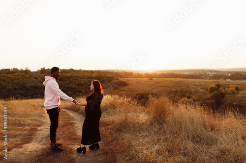 Beautiful couple walking at the field, attractive husband holding hands adorable wife, overjoyed woman smiling, happy family spend time together, weekends outdoors concept © shunevich