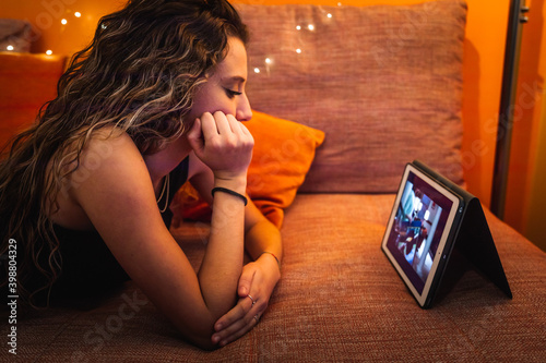 Young caucasic woman watching a series on the sofa