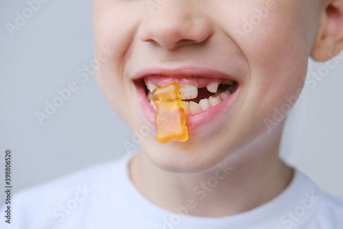 boy  kid holds in his mouth and eats gelatinous sweets  gummy bear  concept of children s delicacy  healthy and unhealthy food  halal food