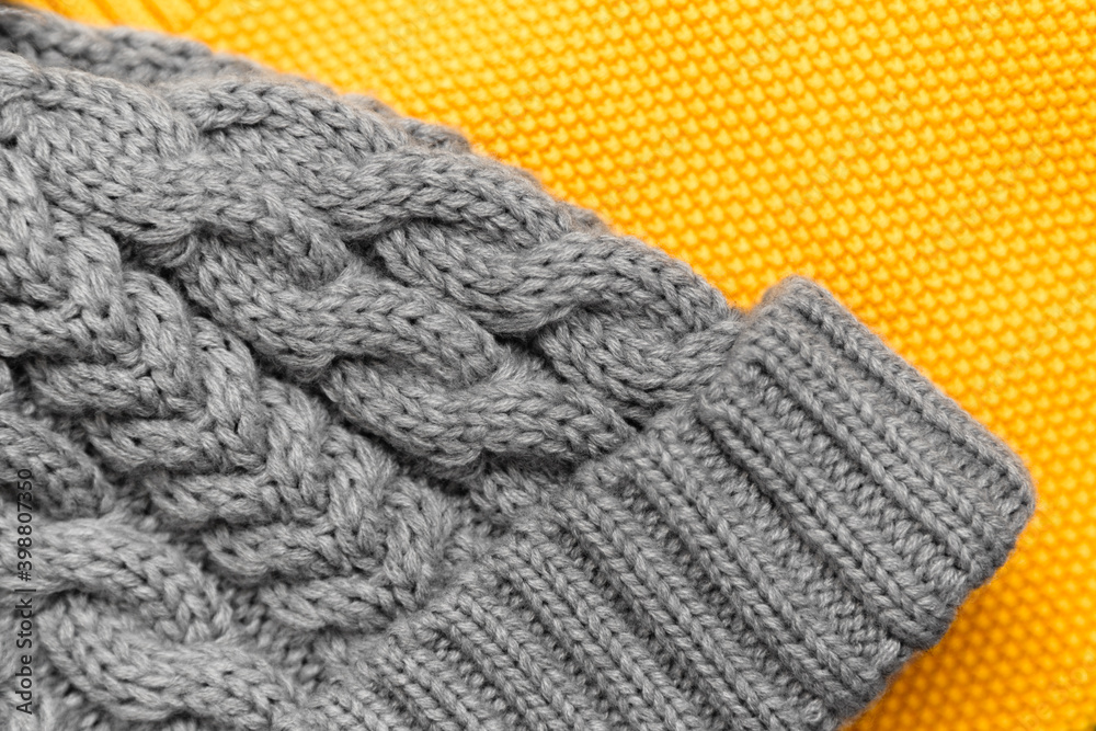 Close up of knitted yellow sweater and gray hat on it in trendy colors. Colors of the 2021 year. Cozy knitted clothing, warm concept Close up of knitted yellow sweater and gray hat on it in trendy colors. Colors of the 2021 year. Cozy knitted clothing, warm concept