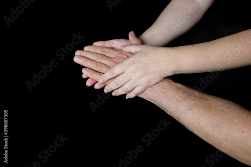male and female hands together on black background, old skin with wrinkles and veins, concept of health, age-related changes, love, tender relationship of a couple in love, isolated image