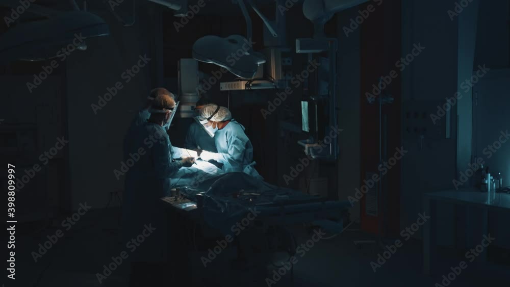 Difficult operation. Zoom view with motion camera at the professional smart serious surgeons wearing medical uniform and working while performing a difficult urgent operation. Work of doctors concept Difficult operation. Zoom view with motion camera at the professional smart serious surgeons wearing medical uniform and working while performing a difficult urgent operation. Work of doctors concept