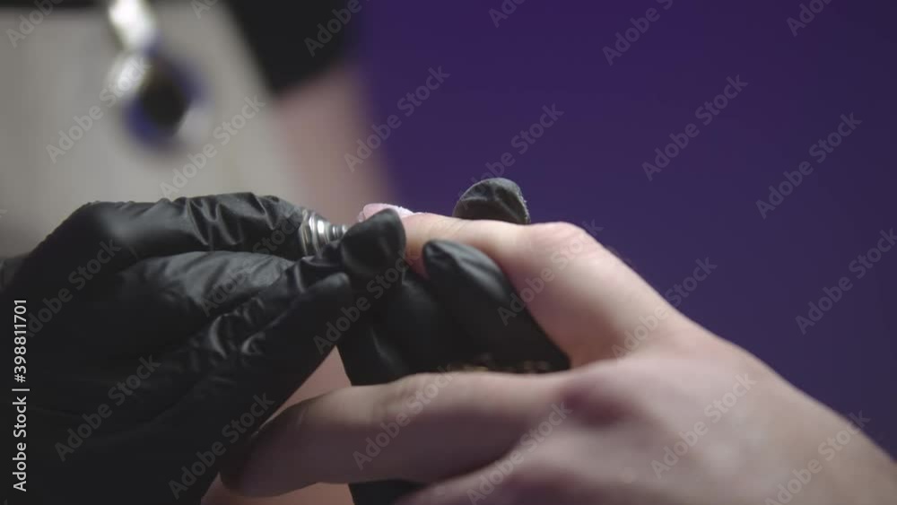 Manicurist in black gloves doing man's nails using a small drilling device Manicurist in black gloves doing man's nails using a small drilling device