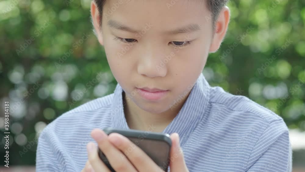4k Young Asian boy play with smartphone in garden 4k Young Asian boy play with smartphone in garden