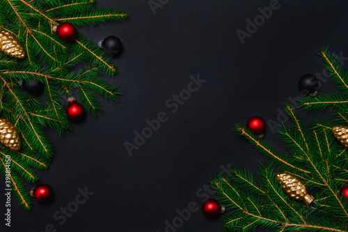 Christmas frame with fresh fir tree branches, balls and pine cones on black background. Dark holiday banner concept. Flat lay top view with copy space