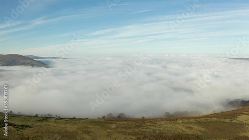 Aerial view flying above low colouds and fog hanging in a rural valley photo