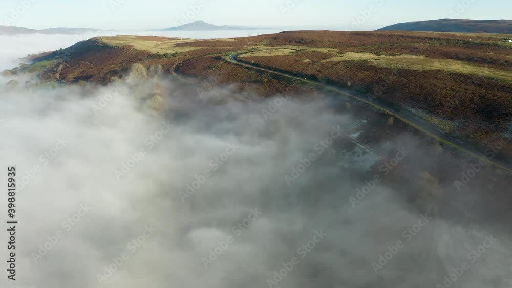 Aerial view of a narrow, winding road on a hillside surrounded by fog and cloud (Wales, UK) Aerial view of a narrow, winding road on a hillside surrounded by fog and cloud (Wales, UK)