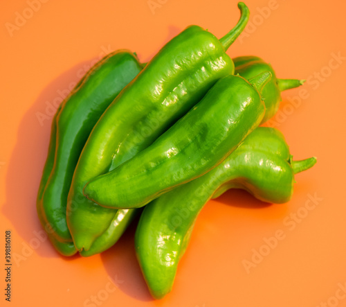 Four Italian Long Sweet Peppers on an orange background
