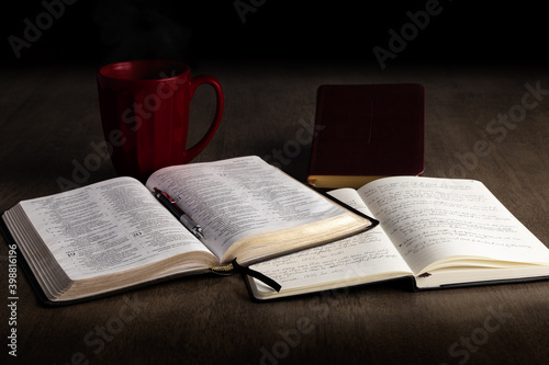 Open bible and notebook with book of prayer and red mug