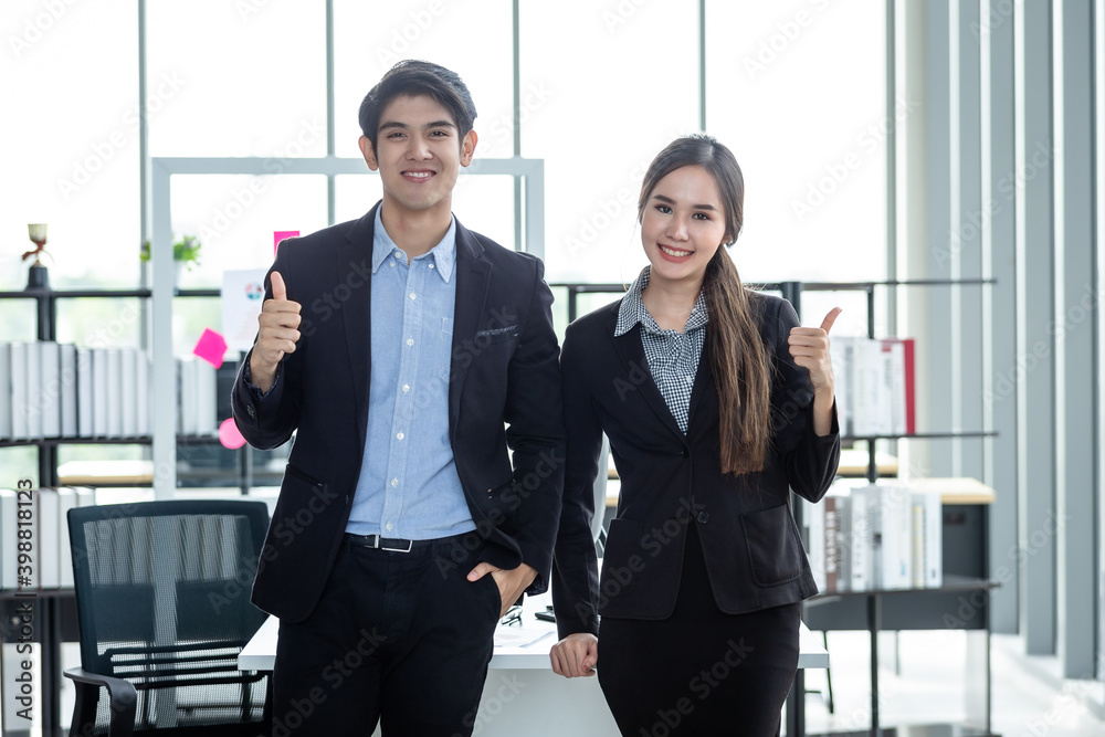 Portrait of a two businessman and businesswoman partners discussing positive adult business showing thumbs up and ideas at meeting in office background Portrait of a two businessman and businesswoman partners discussing positive adult business showing thumbs up and ideas at meeting in office background