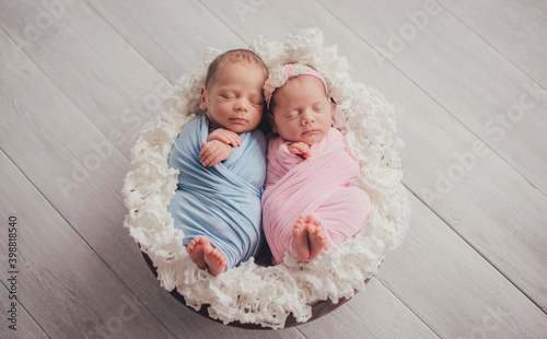Twins are newborn brother and sister. Newborn girl and boy. Sleeping sweetly in a basket.