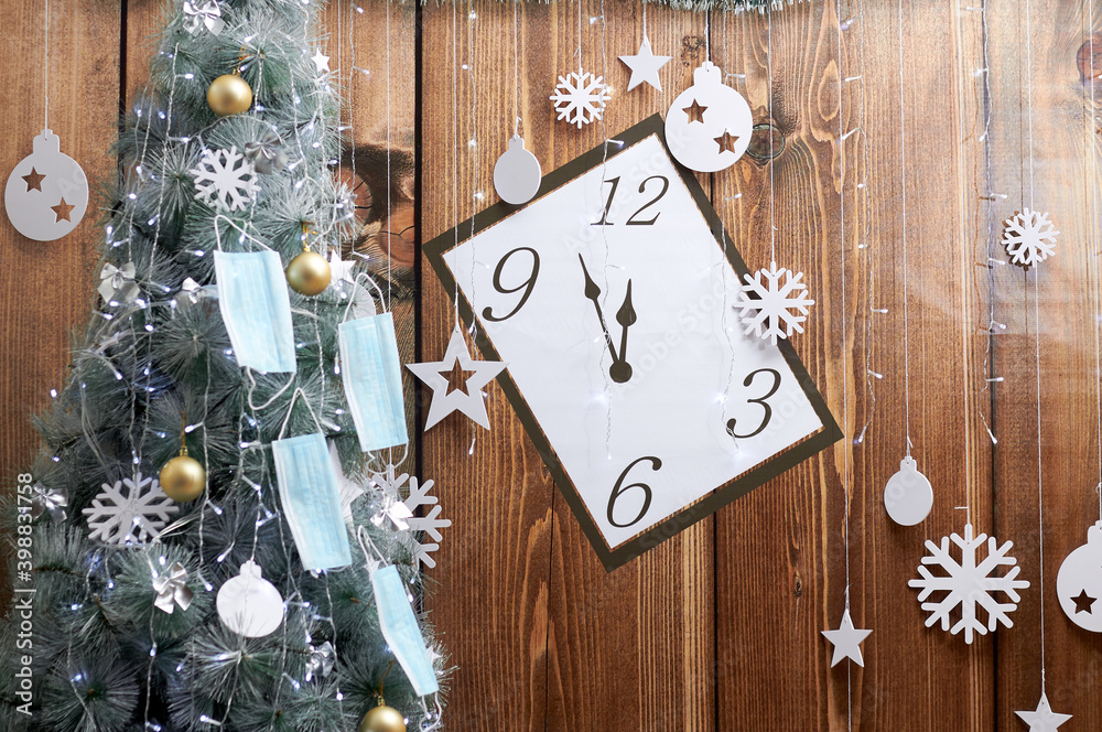 face masks hang on a Christmas tree, on a wooden clock background. Pandemic. face masks hang on a Christmas tree, on a wooden clock background. Pandemic.