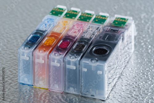 Ein kompletter Satz von Tintenpatronen (mit elektronischen Chips) für einen Tintenstrahldrucker steht auf einem metallischen Hintergrund photo