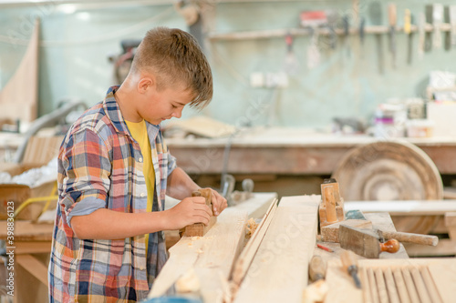 Young boy planed wood in a workshop. Empty space for text