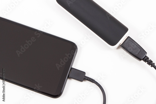 Smartphone with connected plug of powerbank. Telephone charging