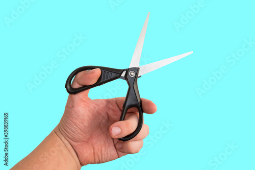 Hairdresser holding scissors for cutting hair or nails on blue background