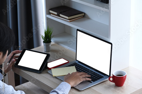 Over head shot of young male working with multiple electronic devices at home office.
