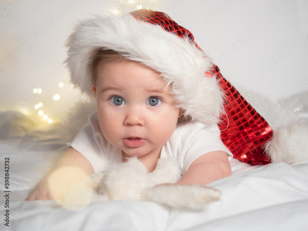 Adorable baby girl in Santa hat lying on the bed Adorable baby girl in Santa hat lying on the bed