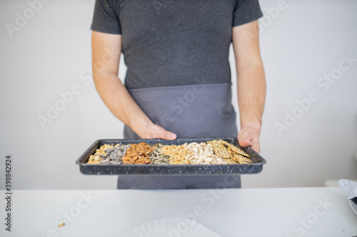 Male hand holding a black tray of nuts and seeds