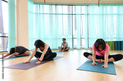 Yoga practice exercise class, group of sporty people practicing yoga lesson at indoor studio, setting together and doing Child pose, working out and exercising for taking care of their body