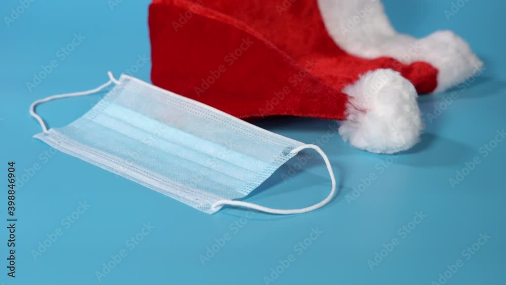 Santa Claus Hat and Medical Mask on a Blue Background. Santa Claus Hat and Medical Mask on a Blue Background.