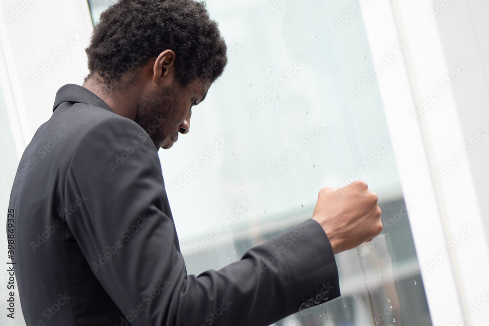 Fototapeta premium Angry upset African black businessman, portrait of failed unhappy black business man punching glass window, concept of work problem, office stress syndrome, economic recession, layoff, unemployment