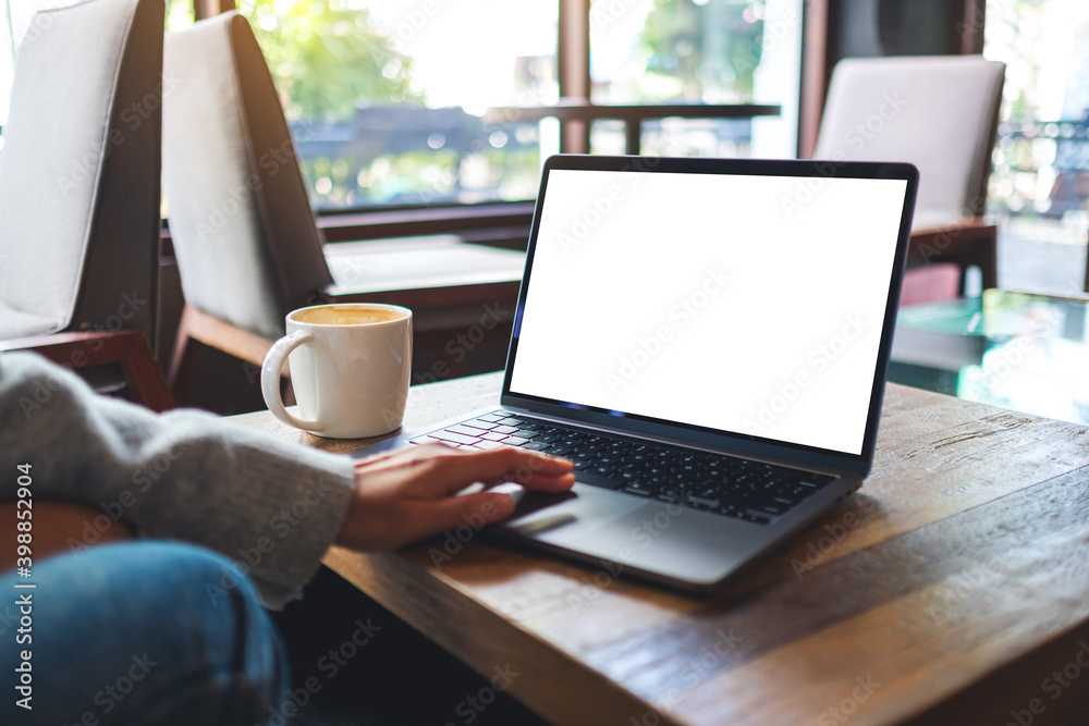 Mockup image of a woman using and touching on laptop touchpad with blank white desktop screen in cafe Mockup image of a woman using and touching on laptop touchpad with blank white desktop screen in cafe