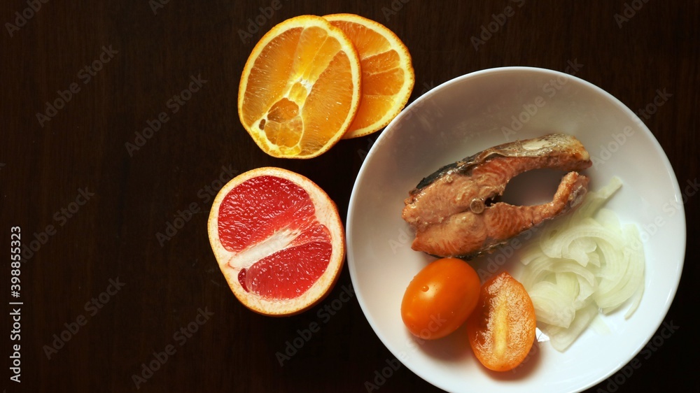 a combination of the taste of red fish and citrus fruits in a ready-made dish of fried chum salmon steak seasoned with grapefruit and orange juice, sliced from half rings of onions and yellow tomatoes a combination of the taste of red fish and citrus fruits in a ready-made dish of fried chum salmon steak seasoned with grapefruit and orange juice, sliced from half rings of onions and yellow tomatoes