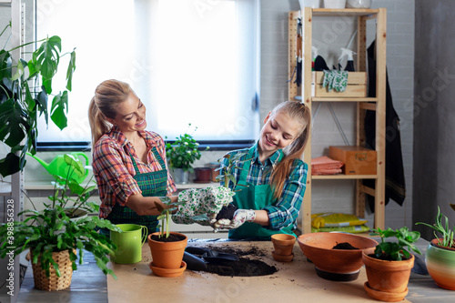 Mum and her daughter at home taking care for flowers and having fun time together