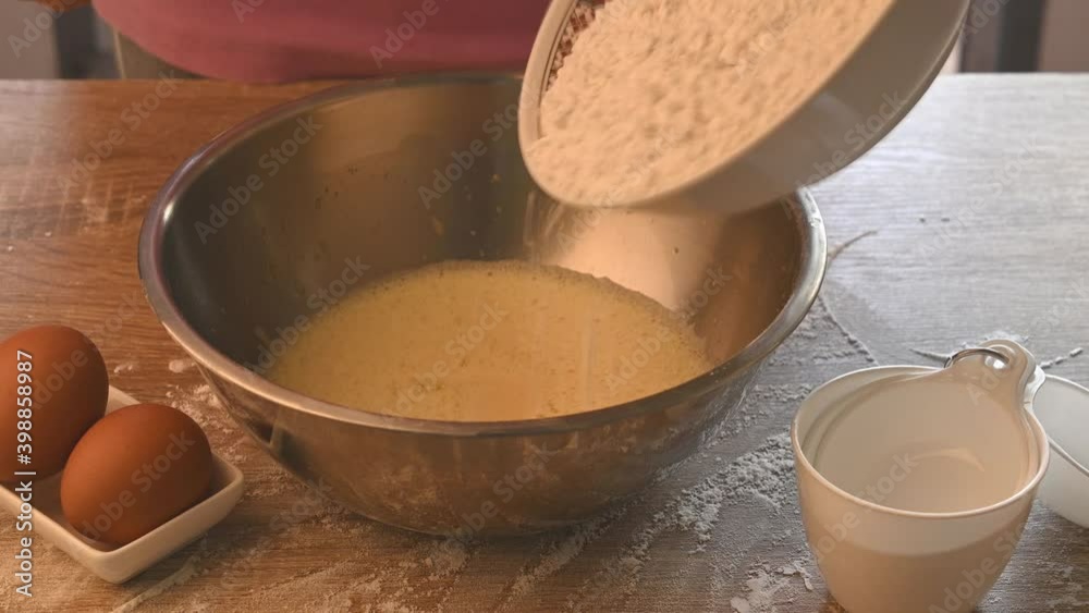 Pouring flour in a bowl and mixing for bakery cooking (cake and cookies)