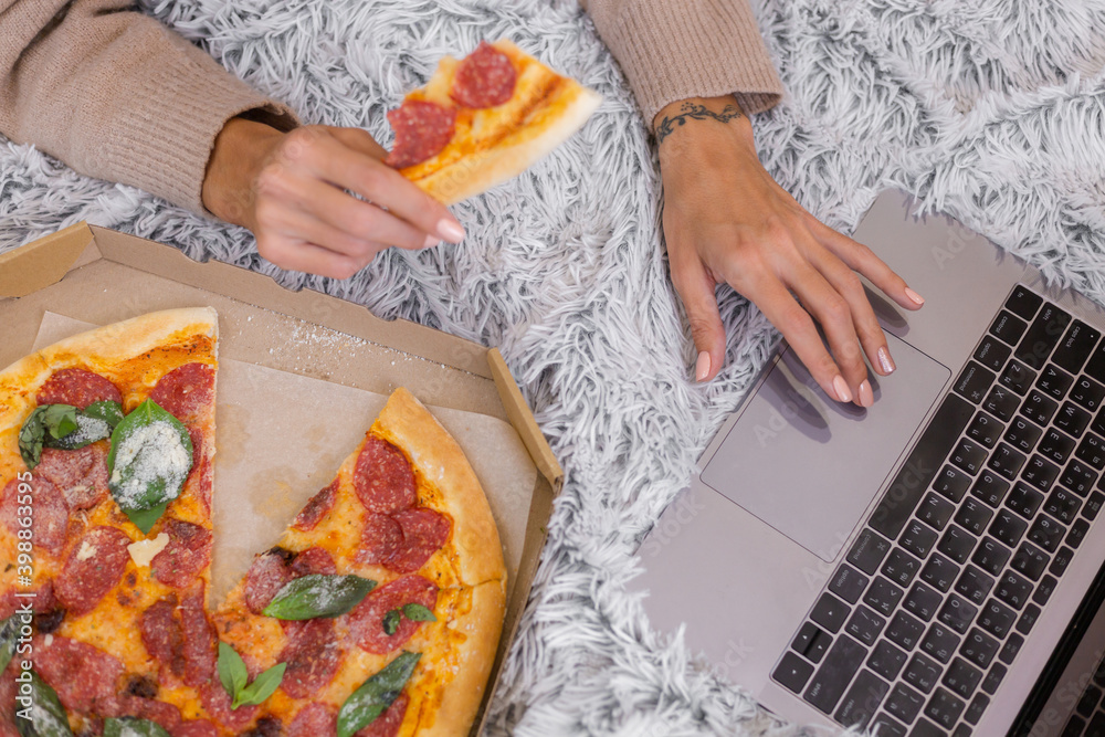 Woman east fast food from delivery on bed in bedroom at home at christmas new year time. Female alone enjoying fat food, pizza. Hungry for carbs.
Woman east fast food from delivery on bed in bedroom at home at christmas new year time. Female alone enjoying fat food, pizza. Hungry for carbs.