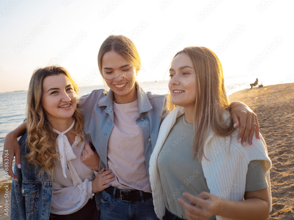 Three friends having fun on the beach, meeting friends. Young women Three friends having fun on the beach, meeting friends. Young women